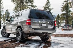 an suv is parked in the snow near some trees