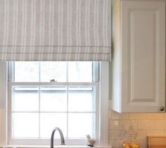 a kitchen with white cabinets and a window