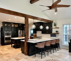 a large kitchen with black cabinets and white counter tops, an island in the middle