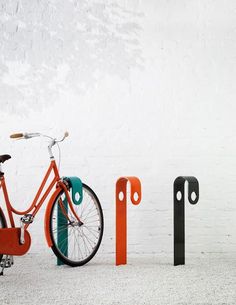 an orange bike is parked next to two black and white poles with numbers on them