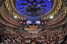 an auditorium full of people with balloons in the ceiling