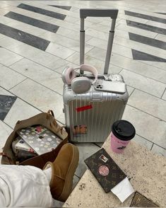 an assortment of luggage sitting on the ground next to a person's feet and handbag