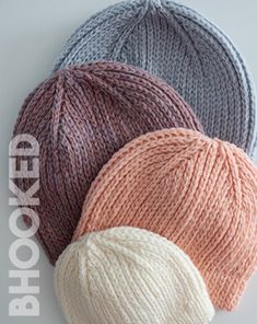 three different colors of knitted hats on top of each other