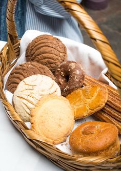 a wicker basket filled with different types of pastries on a white tablecloth