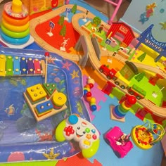 there are many toys on the table and in the play area, including a train set