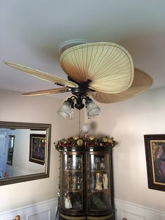 the ceiling fan is hanging from the ceiling in front of a china cabinet with glass doors