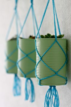 three green planters hanging from the side of a wall with blue string attached to them