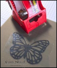 a butterfly cut out on top of a piece of paper next to a plastic container