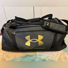 the under armour duffle bag is sitting on the floor in front of a wall