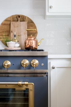 a blue stove top oven sitting inside of a kitchen next to a wooden cutting board