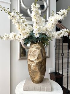 a vase filled with white flowers sitting on top of a table next to a stair case