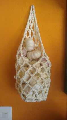 a white net hanging from the side of a wall with sea shells in it and an orange background