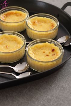 four desserts in small glass dishes on a tray with spoons and utensils