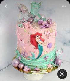 a pink and blue cake with mermaid decorations