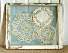 an old frame with lace doily in it on the floor next to a wall