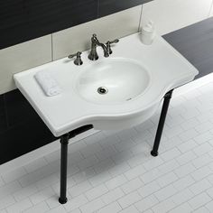 a white sink sitting on top of a black and white tiled floor next to a wall