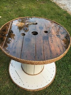 a wooden table sitting on top of a grass covered field next to a white pole