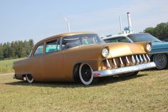 an old car is parked in the grass