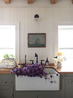 a kitchen sink with purple flowers on the counter