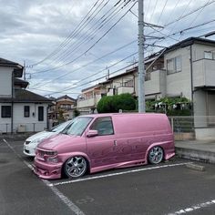 a pink van parked in a parking lot next to two white cars and power lines