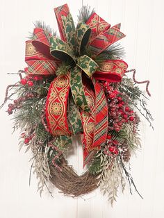 a red and green christmas wreath hanging on a door