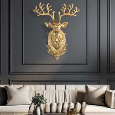 a gold deer head mounted on the wall above a white couch in a living room