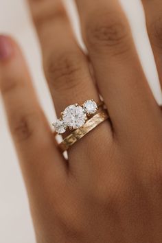 a woman's hand with three diamond rings on top of her finger and the other hand holding an engagement ring