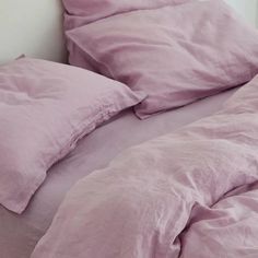 an unmade bed with pink sheets and pillows