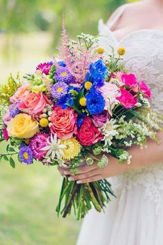 a woman holding a bouquet of colorful flowers