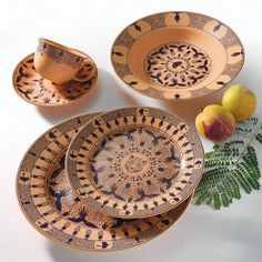 an assortment of decorative plates and bowls with fruit on the table next to each other