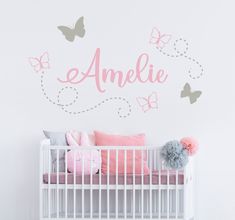 a white crib with pink and grey butterflies on it's wall, next to the name amelie