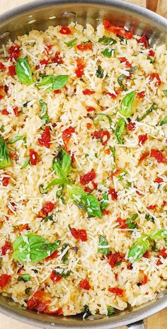 a pan filled with rice and vegetables on top of a wooden table