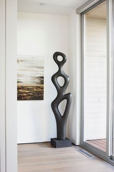 a large black sculpture sitting on top of a hard wood floor next to a window