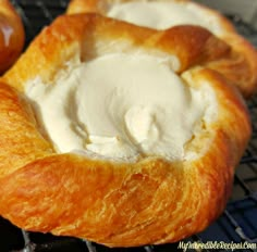 two croissants with cream on them sitting on a cooling rack