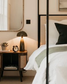 a bedroom with a bed, night stand and mirror on the wall next to it