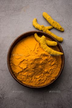 a bowl filled with yellow powder next to two bananas