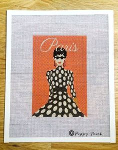 a cross stitch picture of a woman wearing a polka dot dress with the word paris on it