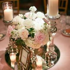 a centerpiece with flowers and candles on a table