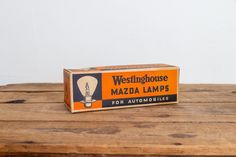 an old westinghouse mada lamps box sitting on a wooden table in front of a white wall