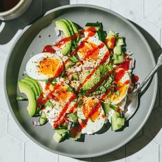 an egg salad with tomatoes, cucumber and avocado on a plate