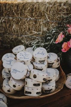 there are many white vases with writing on them and some flowers in the background