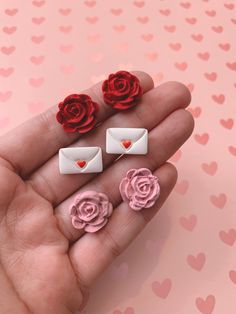 a hand holding three fake roses and two small envelopes with hearts on the background