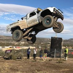 a white truck jumping in the air with people watching