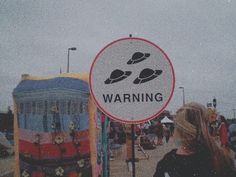 a woman standing next to a sign that says warning in front of a carnival area