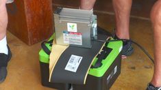 a man standing next to a green and black box with a machine on top of it