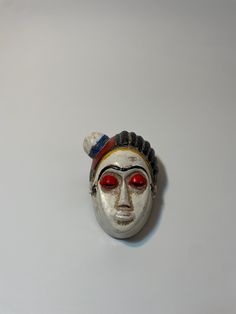 a silver mask with red eyes on a white surface