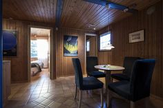 a room with wooden walls and tile flooring has blue chairs around a round table