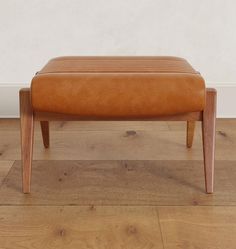 a wooden bench sitting on top of a hard wood floor next to a white wall