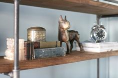 a shelf with books, figurines and an alarm clock on it in a room