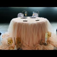 the table is set with two wine glasses and an empty glass vase on top of it